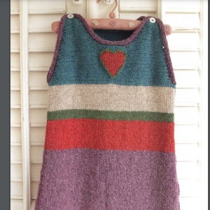 May include: A knitted baby sleeping bag with a heart design on the front. The bag is striped in teal, beige, green, red, and purple.