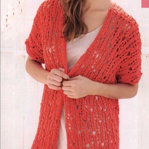 May include: A coral-colored, open-weave cardigan with short sleeves. The long, flowing design features a textured knit pattern. The cardigan is being held closed at the front. This lightweight garment is suitable for layering.