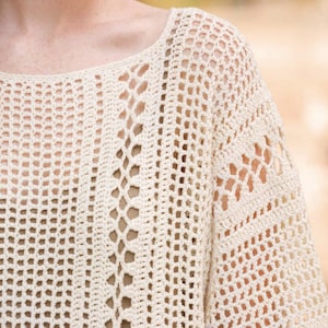 May include: A white crochet top with a loose, open-weave design. The top has a scoop neckline and a relaxed fit.