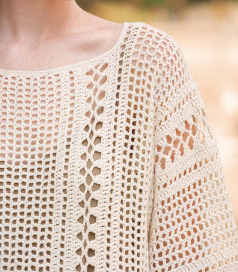 May include: A white crochet top with a loose, open-weave design. The top has a scoop neckline and a relaxed fit.