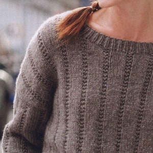 May include: A brown knitted sweater with a ribbed texture and a round neckline.