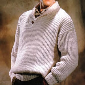 Könnte beinhalten: Ein weißer gerippter Strickpullover mit einem breiten Kragen und einem einzigen Knopfverschluss.