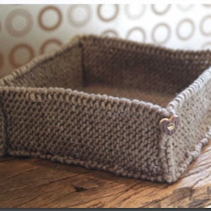 May include: A brown knitted storage basket with a square shape and heart-shaped buttons.