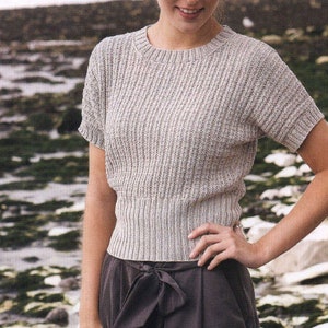 May include: A light gray ribbed knit top with short sleeves and a round neckline.