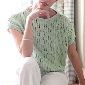 May include: A light green crochet top with a delicate openwork pattern. The top has short sleeves and a round neckline.