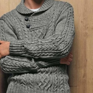 May include: A grey cable knit jumper with a collared neckline and a button fastening.