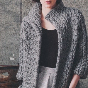 Peut inclure: Un cardigan gris en tricot avec un large col et un motif en tricot torsadé. Le cardigan est ouvert à l'avant et a des manches longues.