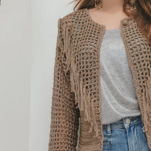 May include: A brown crocheted cardigan with fringe detailing. The cardigan has a loose fit and a V-neckline.