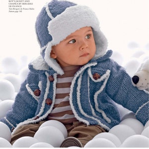 May include: A blue knitted baby jacket with white trim and a matching blue and white knitted hat with a white fur trim. The jacket has a button closure and the hat has ear flaps.