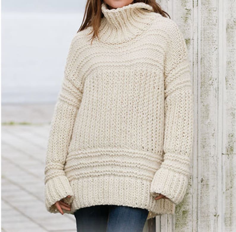 May include: A cream-colored knitted sweater with a turtleneck and long sleeves. The sweater has a relaxed fit and a ribbed texture.