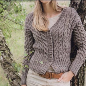 May include: A brown cable knit cardigan with a v-neck and button closure. The cardigan is worn over a white shirt and brown belt.
