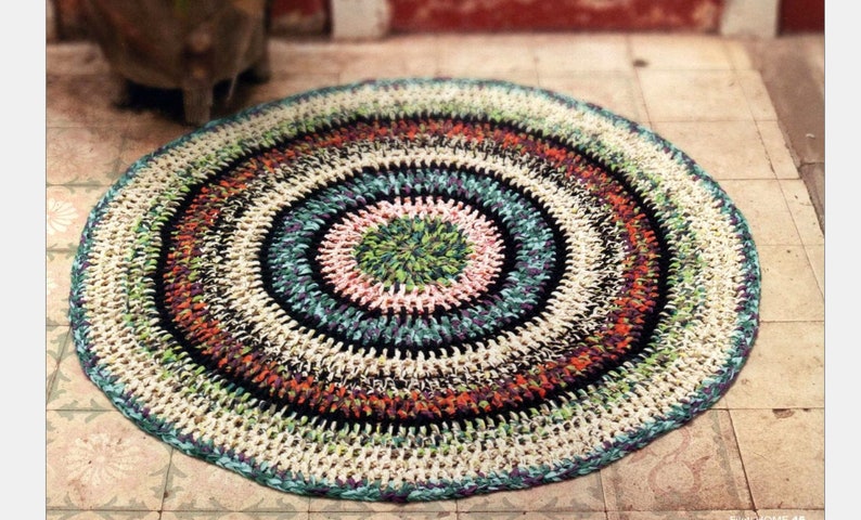 May include: A round, multi-colored crocheted rug with a circular pattern. The rug is made of different colored yarns, including white, black, green, orange, and pink.