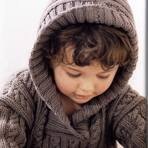 May include: A child wearing a brown knitted hooded sweater with a cable knit pattern. The sweater has a large hood that is pulled up over the child's head.