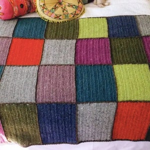 Peut inclure: Une couverture en crochet colorée avec un motif patchwork composé de carrés turquoise, violet, vert, gris, rouge et bleu.