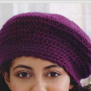 May include: A purple crocheted beret hat. The hat is made with a simple stitch pattern and has a slouchy fit.