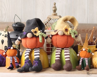 May include: Three crocheted pumpkin gnomes, one in black and orange, one in brown and orange, and one in green and orange, sitting on bowls. The gnomes are wearing hats and have yarn hair.