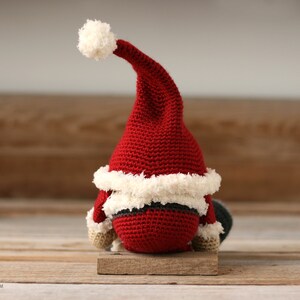 Back view of the  Crochet Santa Gnome sitting on a wood background.