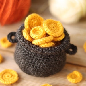 May include: A crocheted pot filled with crocheted gold coins. The pot is dark gray and the coins are yellow.