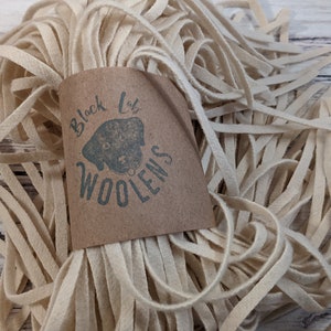 May include: A bundle of off-white wool felt strips, approximately 1/2 inch wide, with a brown paper tag that reads "Black Lab Woolens".