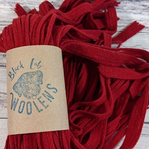 May include: A bundle of red wool yarn with a brown label that says "Black Lab Woolens".