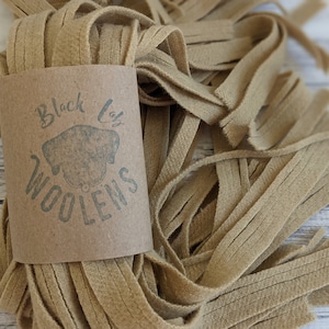 May include: A bundle of tan felt strips, approximately 1/2 inch wide, with a brown paper label that reads "Black Lab Woolens".