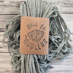 May include: A skein of light green yarn with a brown label that says "Black Lab Woolens".