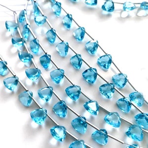 May include: A strand of light blue gemstone beads, each bead is a faceted triangle shape, strung on silver wire.