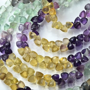 May include: A strand of faceted gemstone beads in shades of green, yellow, and purple. The beads are shaped like small, pointed triangles.