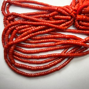 Puede incluir: Una hebra de cuentas de coral naranja brillante. Las cuentas son cilíndricas y tienen un acabado liso y pulido.