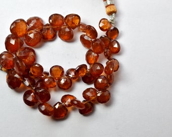 May include: A strand of brown gemstone beads with a tassel on one end. The beads are faceted and have a shiny, translucent appearance.