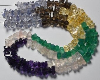 May include: A strand of faceted gemstone beads in various colors, including amethyst, rose quartz, green aventurine, citrine, smoky quartz, and blue topaz. The beads are all roughly the same size and shape, and they are strung on a clear thread.