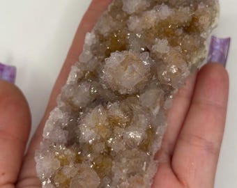 May include: A raw crystal cluster featuring a combination of translucent white quartz points and golden-brown mineral inclusions. The specimen has a jagged, textured surface with numerous small, sharp, multifaceted crystal formations.