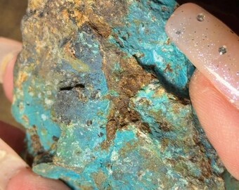 May include: A rough-hewn stone with a striking combination of colors. The rock features vibrant turquoise, deep blues, and earthy browns, creating a visually appealing contrast. The surface has a textured appearance, showcasing natural variations.