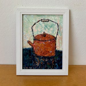 以下が含まれることがあります： 白い額縁に入った油絵で、金属製の取っ手が付いた質感のある錆色のティーポットが描かれています。ティーポットは濃い青色の表面に置かれ、背景は淡い緑色です。筆致は厚く、作品全体を通してはっきりと見ることができます。