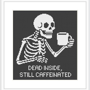 May include: A black and white cross-stitch design features a skeleton holding a coffee mug. The text "DEAD INSIDE, STILL CAFFEINATED" is below the skeleton. The design is framed in a white border.