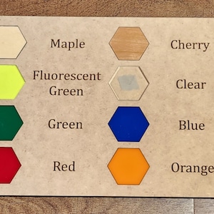 May include: A wooden board with 16 hexagonal color samples. The samples are labeled with wood types like Draftboard, Maple, Cherry, and Walnut, and colors like Fluorescent Pink, Fluorescent Green, Clear, Black, White, Green, Blue, Teal, Yellow, Red, Orange, and Purple.