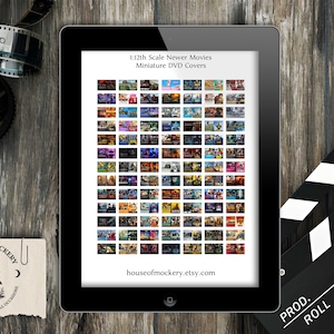 Può includere: Un tablet mostra una stampa digitale di copertine di DVD in miniatura di film più recenti. Il tablet è su una superficie di legno, con strisce di pellicola e una clapperboard nelle vicinanze. Il testo "1:12th Scale Newer Movies Miniature DVD Covers" è visibile.