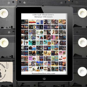 May include: A digital tablet showcasing miniature VHS covers, with the text "1:12th Scale Mixed Genre's Miniature VHS Covers." The tablet is positioned against a background of stacked VHS tapes. A small card with the "House of Mockery" logo is visible.
