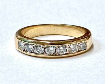 May include: A gold band with a row of small, clear diamonds set in a channel setting.