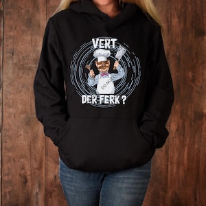 Puede incluir: Sudadera negra con un gráfico blanco de un chef de dibujos animados sosteniendo un cuchillo y una cuchara de madera. El texto "VERT DER FERK?" está impreso debajo del chef.