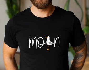 Pode incluir: Uma camiseta preta com um gráfico branco de uma gaivota e a palavra "Morn" escrita em itálico.