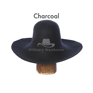 May include: A charcoal gray felt hat with a wide brim and a tall crown. The hat is sitting on a wooden hat block. The text "Millinery Warehouse" is printed on the hat.