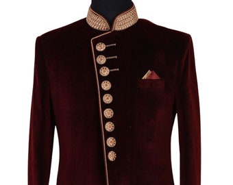 May include: A maroon velvet long-sleeved jacket with a mandarin collar, gold trim, and gold buttons. The jacket has a single front slit and a pocket on the left side. The text "AJIRNA ROYAL DESIGNER" is printed on the bottom right corner of the jacket.