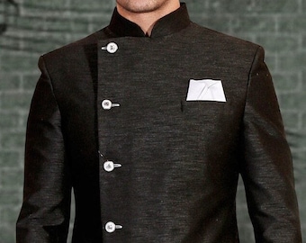 May include: A black long-sleeved jacket with a mandarin collar and a single button closure. The jacket has a unique asymmetrical design with a long, flowing tail and a diagonal seam on the front. The jacket has several silver buttons down the front.