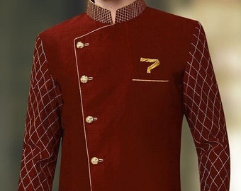 May include: A maroon long-sleeved kurta with a high collar and gold buttons. The sleeves have a diamond pattern with gold thread embroidery. The kurta has a side slit and a gold pocket on the chest.