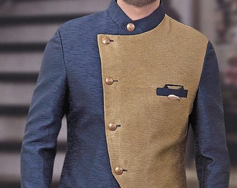 May include: A navy blue and tan suit jacket with gold buttons. The jacket has a unique asymmetrical design with a tan panel on the right side and a small pocket. The sleeves are long and the pants are tan.