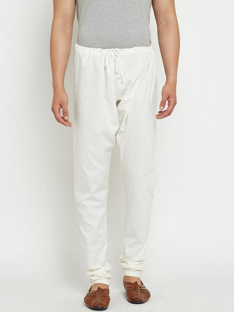 May include: White cotton trousers with a drawstring waist and a slim fit. The trousers are cuffed at the ankles.