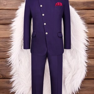 May include: A purple suit with a mandarin collar and a single button closure. The suit has a pocket square in a burgundy colour.