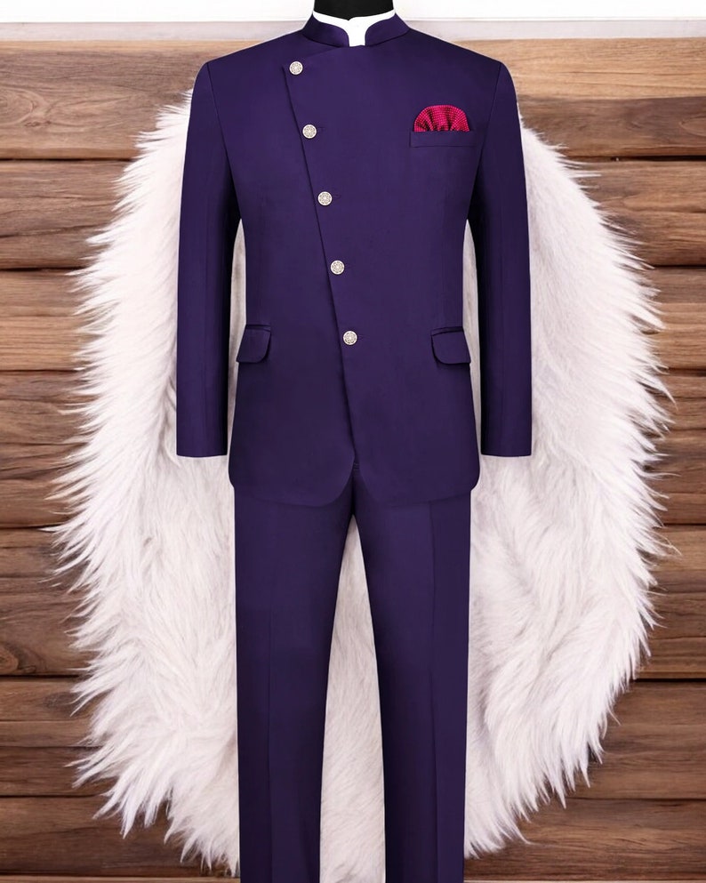 May include: A purple suit with a mandarin collar and a single button closure. The suit has a pocket square in a burgundy colour.