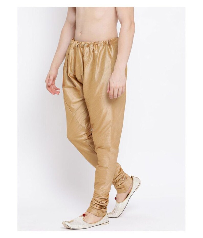Pode incluir: Cal&ccedil;a de cor dourada com cintura de cord&atilde;o e ajuste fino. A cal&ccedil;a &eacute; feita de um tecido brilhante e tem um detalhe franzido nos tornozelos.